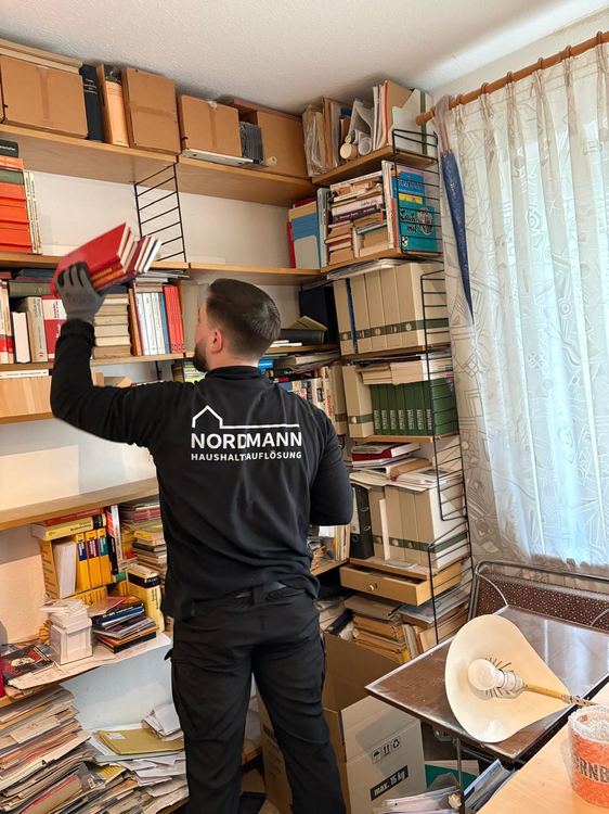 Mitarbeiter von NORDMANN räumt eine Bücherwand aus